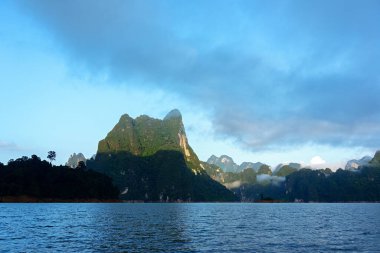 Sabah ışığında kireçtaşı dağ sırasının aydınlığı ve gölgesi Tayland 'ın Chiewlarn Gölü' nde sis.