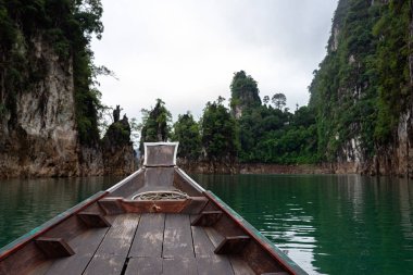 Gölde küçük ahşap bir tekne. Büyük kireçtaşı kayaları ve arka planda sis var. Tayland, Surat Thani 'de..