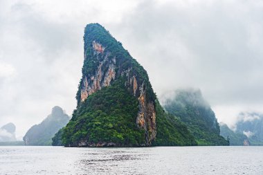 Tayland 'ın Phang Nga Körfezi' ndeki Koh Panyee adası yakınlarında beyaz bulutlu kireçtaşı adası ve yüksek uçurum..
