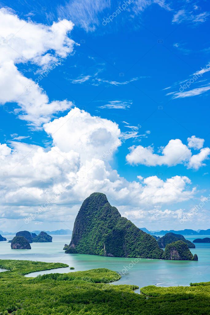 Limestone islands and green mangrove forest with blue sky and white clouds in Phang Nga Bay, Thailand.