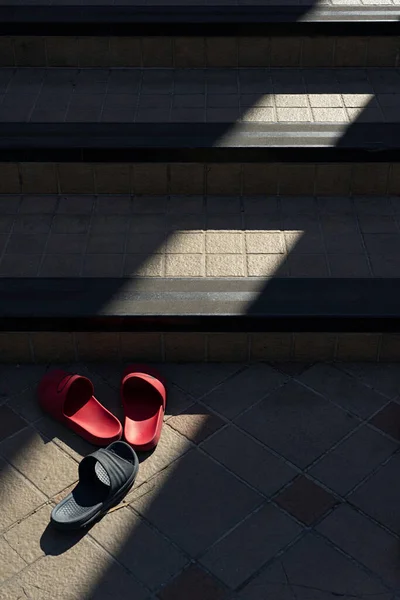 Light and shadow on slippers and stone stairs in Thai Buddhist temple.