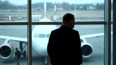 Yaşlı adam, tam yükseklikte stand Havaalanı terminal penceresi, siluet görünümü gaze. Havaalanında uçak bakar.