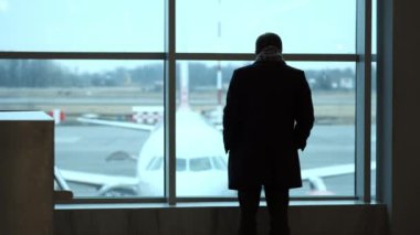 Yaşlı adam, tam yükseklikte stand Havaalanı terminal penceresi, siluet görünümü gaze. Havaalanında uçak bakar.