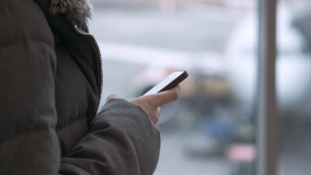 Жінка-мандрівник чекає на від'їзд і використовує свій мобільний телефон. молода дівчина пише повідомлення. Очікування рейсу — стокове відео