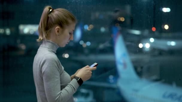 Žena cestujícím čekání na odlet a pomocí její mobil. mladá dívka píše zprávu. Čekání na let — Stock video