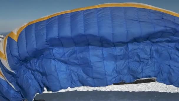 Väcker den segel flygeln av paraglider. Han börjar ta fart, bryter bort från marken, springer iväg. Paragliding i vinter. — Stockvideo