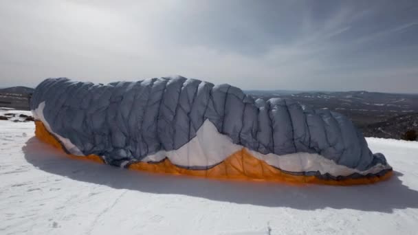 Hebt den Segelflügel des Gleitschirms. Er hebt ab, löst sich vom Boden, rennt davon. Gleitschirmfliegen im Winter. — Stockvideo