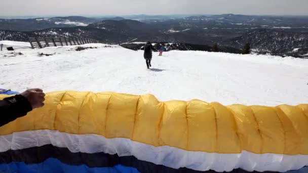 Levanta el ala de vela del parapente. Empieza a despegar, se aleja del suelo, huye. Parapente en invierno . — Vídeo de stock