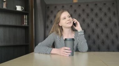 Genç güzel kız yanında smartphone kafede çağırır. Sabah işe gitmeden önce kahve içiyor. Konsept: Kahvaltı, sakin ol, kahve, iş