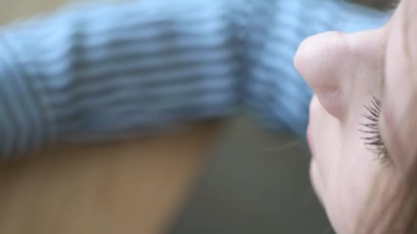 Een mooi meisje in een stijlvol café drinkt koffie in de ochtend voor het werk. Zit tegenover het venster. Hij drinkt koffie uit een kartonnen zwart glas. Close-up. — Stockvideo