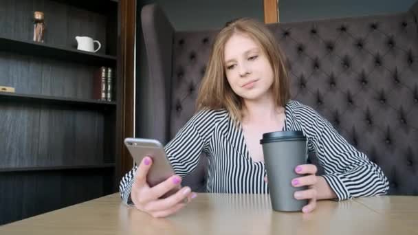 Menina Smartphone usando aplicativo no telefone beber café sorrindo no café. Jovem profissional feminino casual bonita no telefone móvel . — Vídeo de Stock