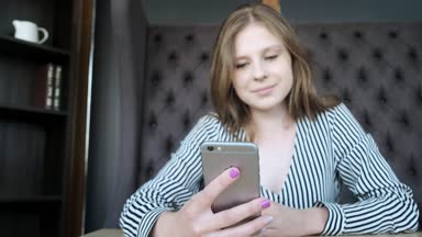 Genç kız güzel şık bir kafe, bir akıllı telefon kullanır uygulama kullanır. Pencerenin oturur.