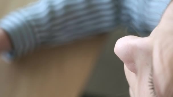 Ein junges schönes Mädchen in einem stilvollen Café trinkt morgens vor der Arbeit Kaffee. sitzt dem Fenster gegenüber. Er trinkt Kaffee aus einem schwarzen Pappglas. Nahaufnahme. — Stockvideo