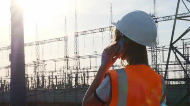 Bir kız mühendisi olarak beyaz bir kask ve bir portakal koruyucu yelek teller ve elektrik ile bir güç istasyonu olup olmadığını denetler. Yeni sahiplik sorunu çözer.