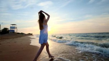 Beyaz elbiseli bir kız gün batımında denize girer. Deniz ve plaj ile mutluyum. Özgürlük karşılaşmış. Suya gider,.