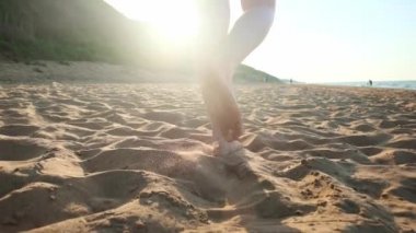 Kumsalda ıslak kumların üzerinden yürüyen kadın. Kadın ayakları üzerinde sarı kum deniz kabuklarını adım. Mutluluk ve özgürlük.