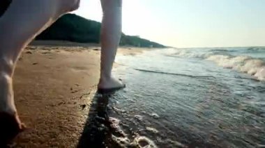Kız su kenarı yürüyüş. Kıyı kum üzerinde kadın. Kamera sonra erkek hareket ediyor.