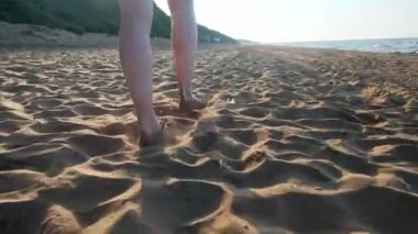 Kumsalda ıslak kumların üzerinden yürüyen kadın. Kadın ayakları üzerinde sarı kum deniz kabuklarını adım. Mutluluk ve özgürlük.