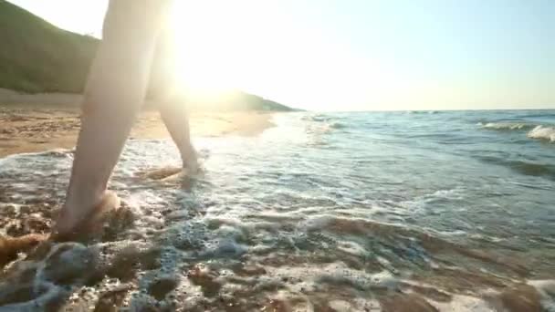 Κορίτσι περπατώντας κατά μήκος της άκρης ύδατα. Γυναίκα πηγαίνει κατά μήκος της ακτής στην άμμο. Η κάμερα είναι κίνηση μετά το θηλυκό. — Αρχείο Βίντεο