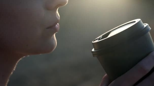 Ragazza sexy in costume da bagno nero bere caffè da un bicchiere di cartone sulla spiaggia. Sera al tramonto vicino al mare o all'oceano . — Video Stock