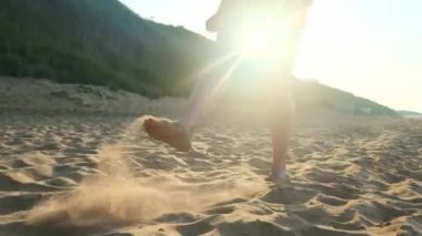 Kumsalda ıslak kumların üzerinden yürüyen kadın. Kadın ayakları üzerinde sarı kum deniz kabuklarını adım. Mutluluk ve özgürlük.