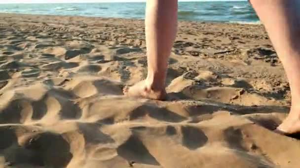 Mujer caminando sobre arena mojada en la playa. Los pies femeninos pisan la arena amarilla de las conchas marinas. Felicidad y libertad . — Vídeo de stock