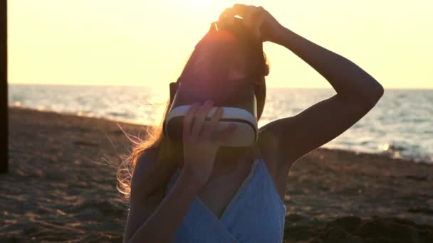 Молода жінка використовує окуляри віртуальної реальності на пляжі. Сексуальна дівчина отримує досвід використання VR-гарнітури влітку на морському фоні . — стокове відео