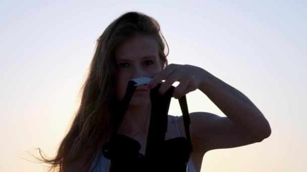 Young woman uses a virtual reality glasses on the beach. Sexy girl getting experience in using VR-headset at summer on sea background. — Stock Video