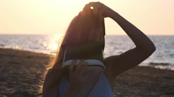 Mujer joven utiliza unas gafas de realidad virtual en la playa. Sexy chica consiguiendo experiencia en el uso de VR-auriculares en verano en el fondo del mar . — Vídeo de stock