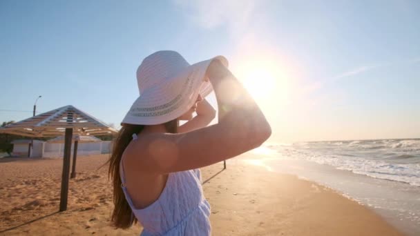 Seksi kız denize bakarak. Bir kız bir şapka ve gözlük okyanusa doğru bir görünüm için arıyor. Bir sol, kaybetti. — Stok video