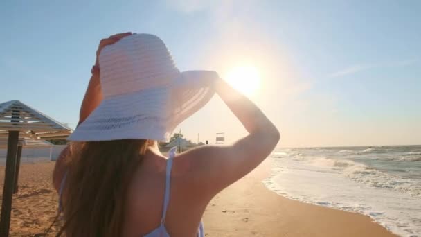 Ragazza sexy guardando il mare. Una ragazza con cappello e occhiali sta cercando uno sguardo verso l'oceano. Uno a sinistra, perso . — Video Stock