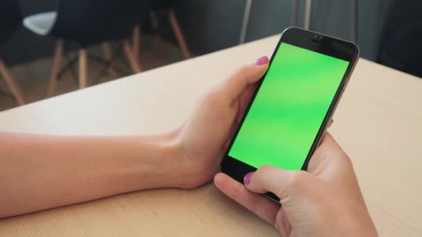 Красива дівчина тримає смартфон в руках зеленого екрану, рука людини тримає мобільний смартфон з зеленим екраном на білому тлі, нова концепція технології — стокове відео
