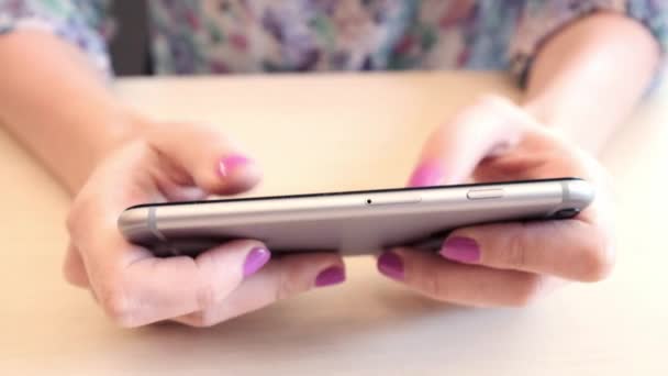 Η κοπέλα στο καφέ κατέχει ένα smartphone. Παίζετε το παιχνίδι σε ένα smartphone. Παίζει στο το app. εξαπολύοντας μόνος. — Αρχείο Βίντεο