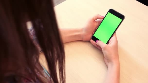 Mooi meisje houdt een smartphone in de handen van een groen scherm groen scherm, hand van man met mobiele smartphone met chroma key groen scherm op witte achtergrond, nieuwe technologie concept — Stockvideo
