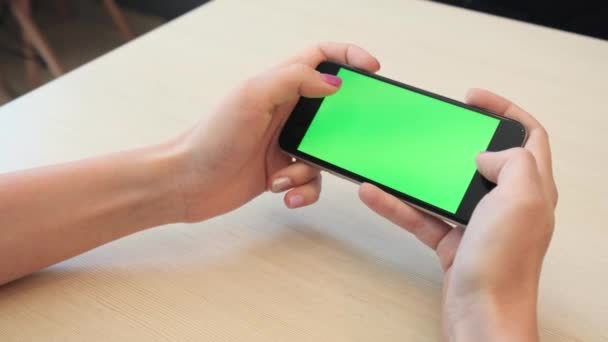 美丽的女孩手持智能手机在绿色屏幕绿色屏幕的手中 扫他的手在屏幕上向下 — 图库视频影像
