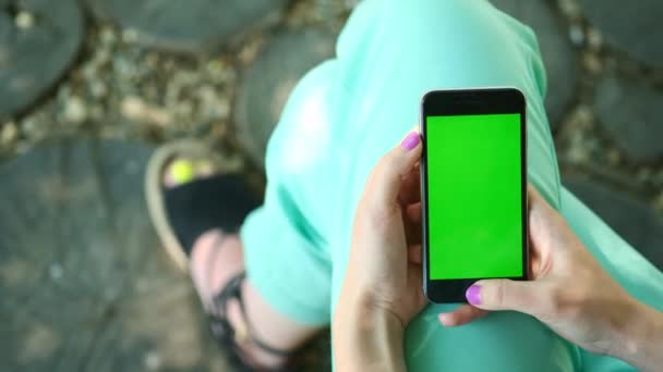 Vacker flicka håller en smartphone i händerna på en grön skärm grön skärm, handen man hålla smart mobiltelefon med chroma key grön skärm på vit bakgrund, ny teknik koncept — Stockvideo