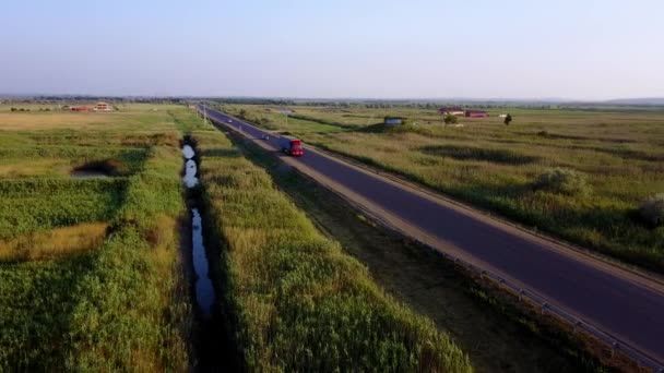 4k antenowe: wysokie loty powyżej kontenera ciężarówki naczepy, transport towarów na ruchliwej autostradzie w całym kraju w piękne letnie wieczory. Ruchu, jazdy i prędkości na autostradzie zajęty w golden sunset — Wideo stockowe