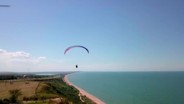 Вид с воздуха. Параплан пролетает над береговой линией. Крыло параплана раздуто ветром. Ряд моря и леса . — стоковое видео