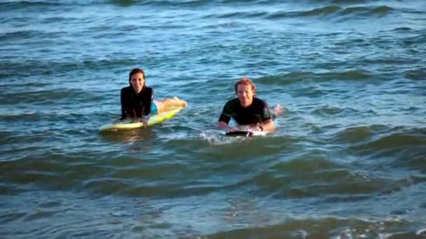Два серфера плавают на досках для серфинга в открытом море, ожидая волны — стоковое видео