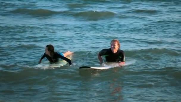 Dwóch surferów pływać na deski surfingowe na otwartym morzu, czekając na fali — Wideo stockowe