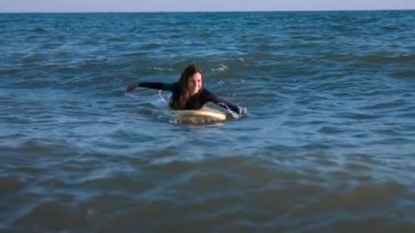 Güzel ince kız denizde sörf tahtası üzerinde yüzer. Denizde profesyonel serfengist.