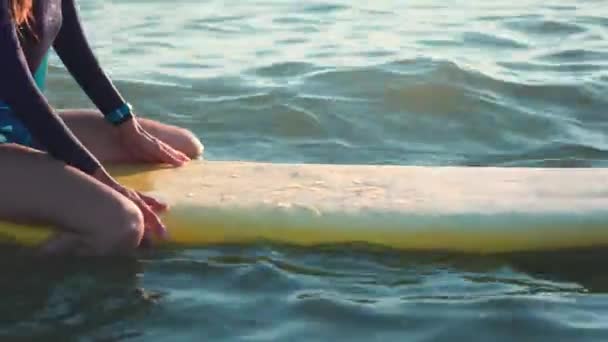 Genç batımını sörf kız ince. Sarı tahtası açık denizde yüzen, bir dalga için bekler ve horizon adlı görünüyor. Profesyonel bir wetsuit giyer. — Stok video