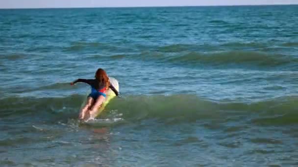 Mooi slank meisje drijvend op een surfplank in de zee. Professionele serfengist op zee. — Stockvideo