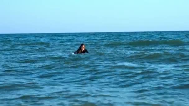 Beautiful slim girl floating on a surfboard in the sea. Professional serfengist at sea. — Stock Video