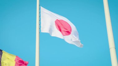 Temiz mavi gökyüzü karşı ağır çekimde sallayarak Japonya bayrağı.