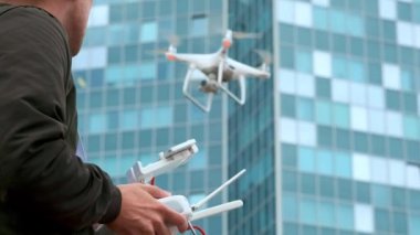 Genç bir adam bir adam bir quadrocopter modern kontrol paneli ve Rc bir verici ile kontrol eder. Drone kamerayla filme ve uçan adam