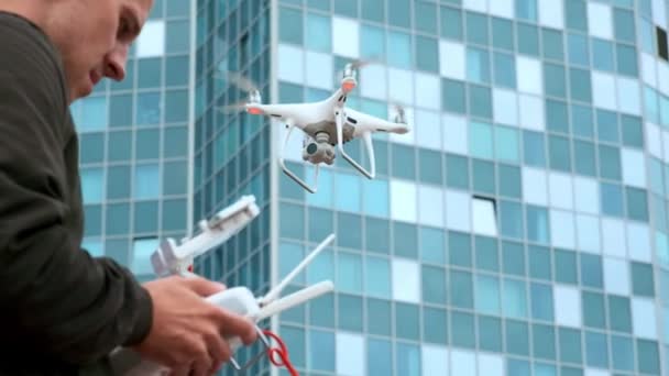 Um jovem um homem controla um quadricóptero com um painel de controle moderno e um transmissor RC. Homem voando e filmando com câmera drone — Vídeo de Stock