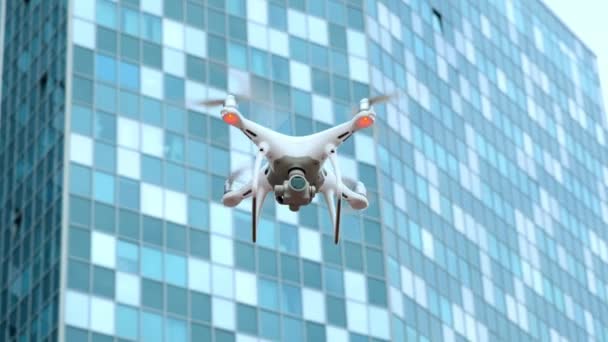 Blanco moderno quadcopter vuela y dispara vídeo en la ciudad, en el contexto de un edificio de negocios industrial — Vídeo de stock