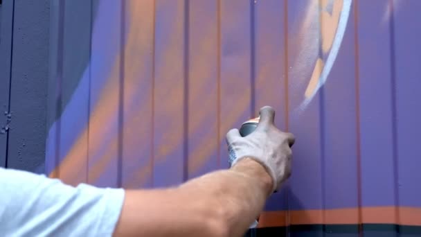 Ένας νεαρός άντρας με ένα κουτί μπογιά εφιστά γκράφιτι στον τοίχο. Ένα χέρι γκρο πλαν. — Αρχείο Βίντεο