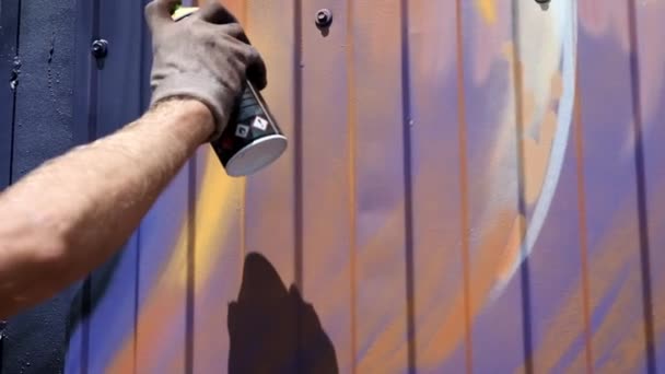 Egy fiatal srác a can of festék felhívja a graffiti a falon. Egyrészt közelről.